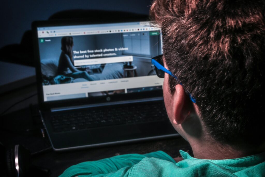 Khumbu digitals Close-up of a person using a laptop to browse stock photos online in dim lighting.resembling digital marketing stratergies