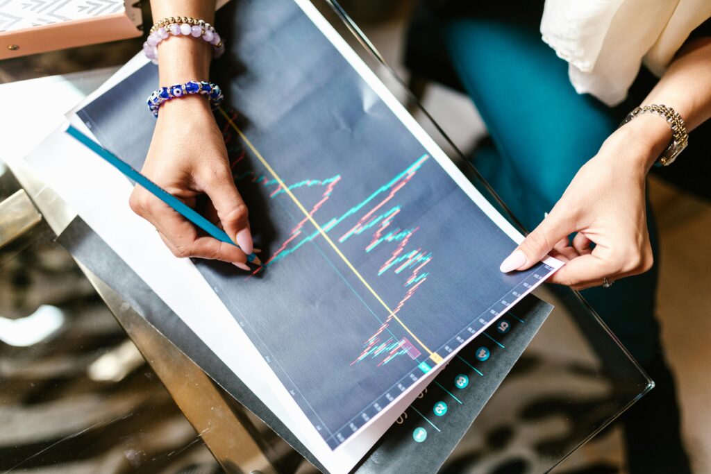 Graphs Woman analyzing financial graph with a printout on a glass table holding a pencil. digital marketing growth stratergies.